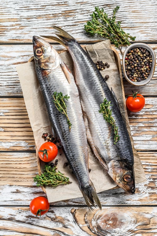 Preview: Salted Dutch herring on paper with spices. White background. Top view