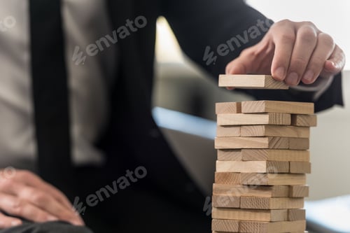 Preview: A close up of a business man carefully building a tower