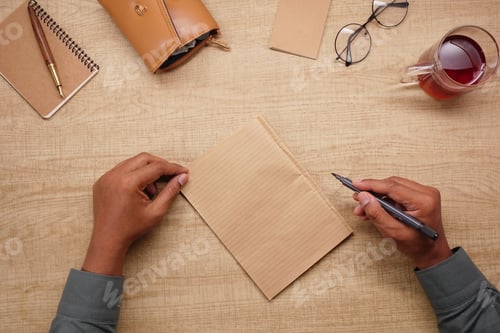 Preview: Person writes on brown paper at wooden table