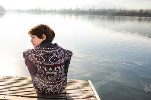 Preview: Boy looking sideways from lakeside pier, rear view, Lake Como, Lecco, Lombardy, Italy