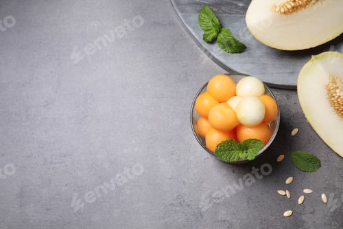 Preview: Melon balls and mint in glass on grey table, flat lay. Space for text