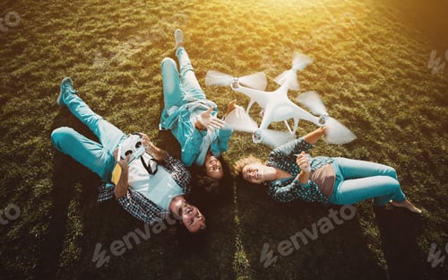 Preview: Company of three persons on the grass and flying drone