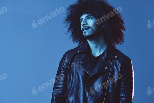 Preview: Portrait of fashion man with curly hair on blue background multinational, colored light, black