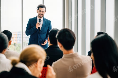 Preview: A diverse audience of colleagues sits and attentively listens as business leaders present their