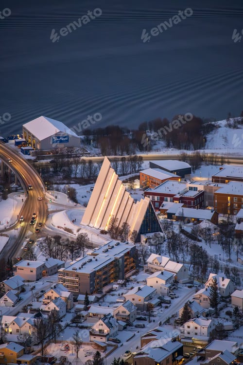 Preview: Aerial view of the Arctic Cathedral in Tromso, Norway surrounded by snowy buildings and roads.
