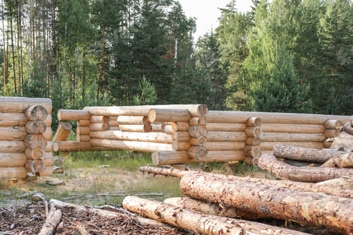 Preview: Wooden a log houses under construction with building materials lying nearby