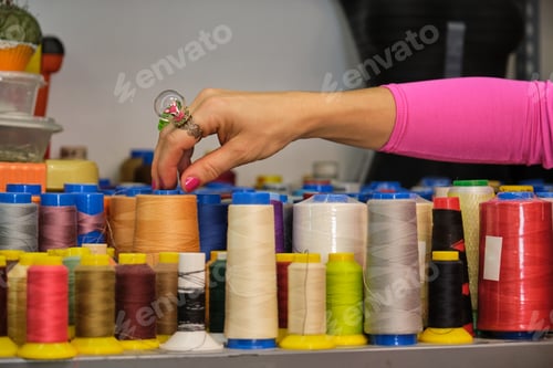 Preview: Unrecognizable dressmaker with colorfull clothes choosing a thread.