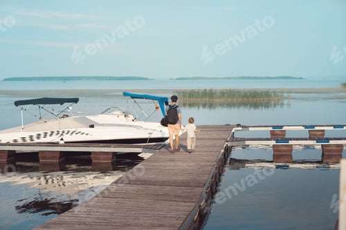 Preview: Behind view of father and son walking on boats pier. Summer vibes