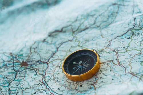Preview: Close up of compass on paper map guide. Travel and adventure lifestyle concept. Planning road