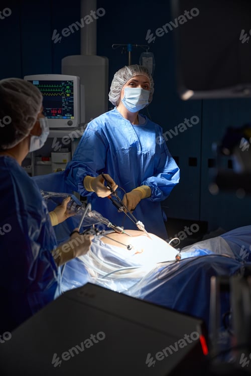 Preview: Medical team performing surgery in dark operating room in hospital