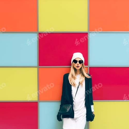 Preview: Fashionable blonde standing against a bright wall. urban style