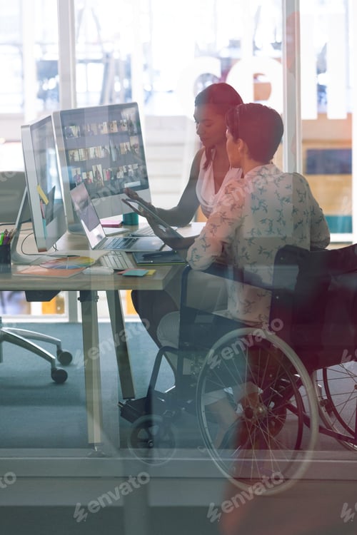 Preview: Diverse female graphic designers working together at desk in a modern office.