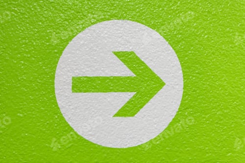Preview: Arrow on a white circle isolated on a green wall showing the direction
