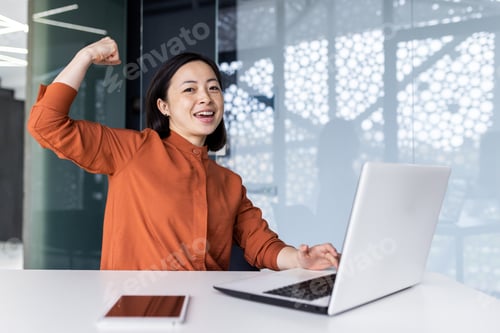 Preview: A young Asian woman student studying using a laptop in a co-working space. Satisfied with the test
