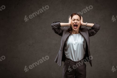 Preview: brunette woman standing and touching head while screaming on grey
