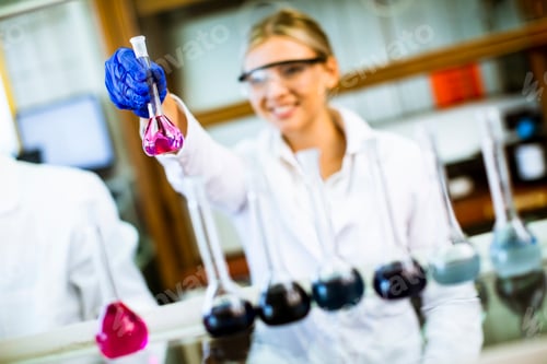 Preview: Young female scientist examining liquid in biochemical lab