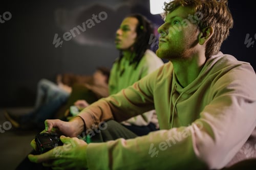 Preview: KYIV, UKRAINE - FEBRUARY 13, 2023: Young man playing video game with blurred multiracial friend in