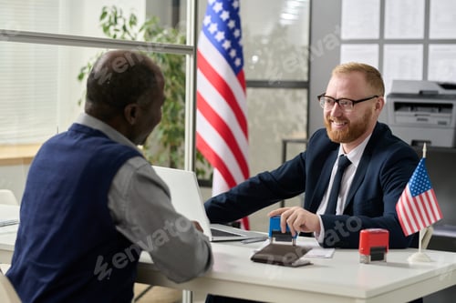 Preview: Friendly smiling worker consulting senior man in US immigration office