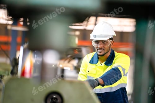 Preview: Production engineers in safety wear are assisting adjusting and maintaining CNC or factory machine