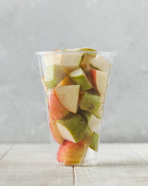 Preview: Pieces of ripe and juicy apples and pears in a transparent plastic cup.