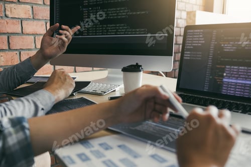 Preview: Two software developers are using computers to work together with their partner at the office desk.