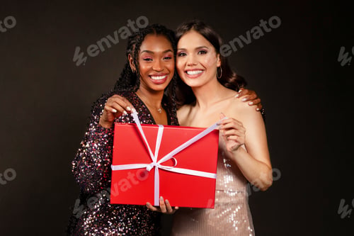 Preview: Cheery multiethnic girlfriends holding big red gift box, Christmas celebration
