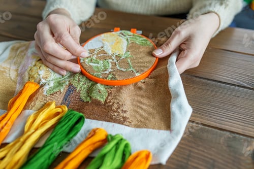 Preview: Making embroidery on canvas by women's hands in beige tones. Hobby and DIY concept