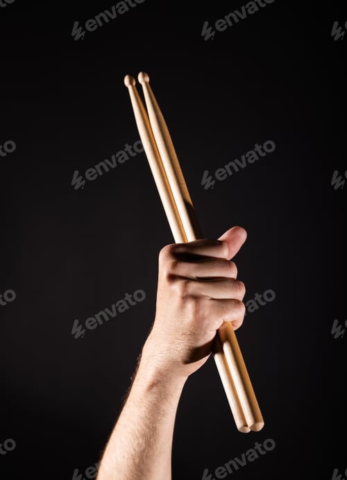 Preview: Close up woman hand with red nails holding two drumsticks over black background, side view