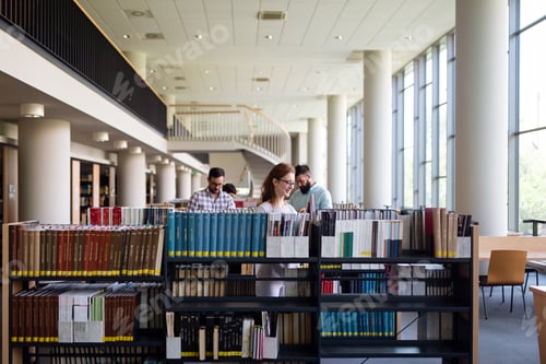 Preview: Happy young university students studying with books in library. Group of people in college library.