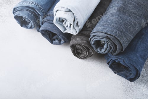 Preview: Stack of different rolled jeans on white background