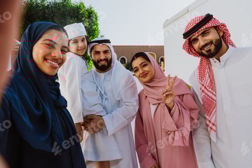 Preview: Emirati family standing together smiling in traditional attire