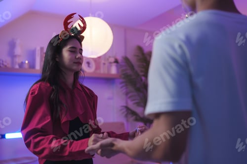 Preview: Young woman wearing reindeer antlers holding hands with partner