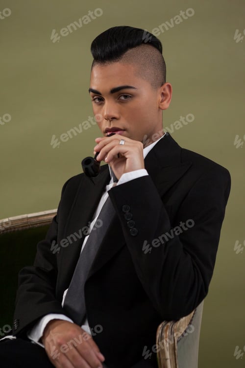 Preview: Portrait of transgender woman holding smoke pipe while sitting on chair