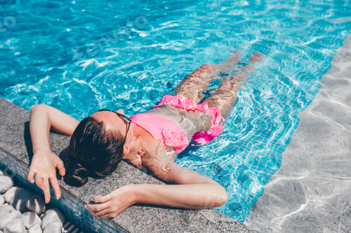 Preview: Young beautiful woman enjoying summer vacation in luxury swimming pool