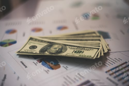 Preview: Stack of Money on Financial Reports and Charts