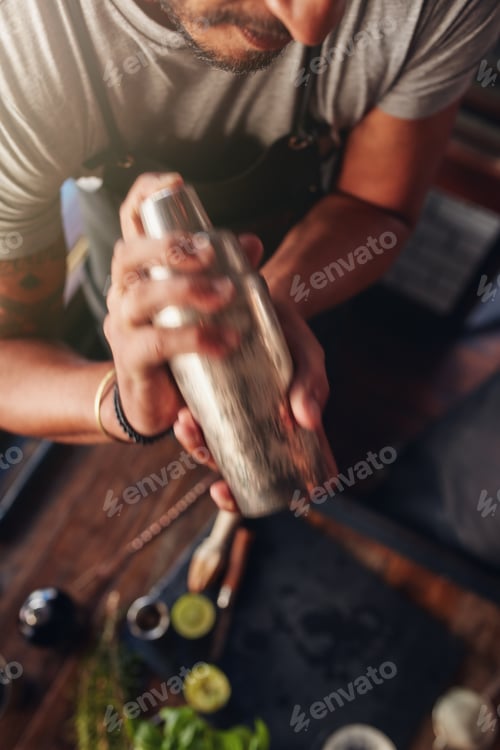 Preview: Bartender mixing drink in cocktail shaker