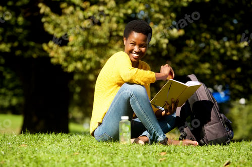 Preview: african american woman smiling with book in park