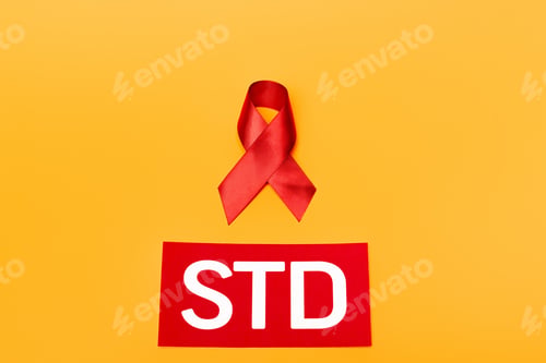 Preview: top view of red ribbon as hiv awareness near std lettering isolated on orange