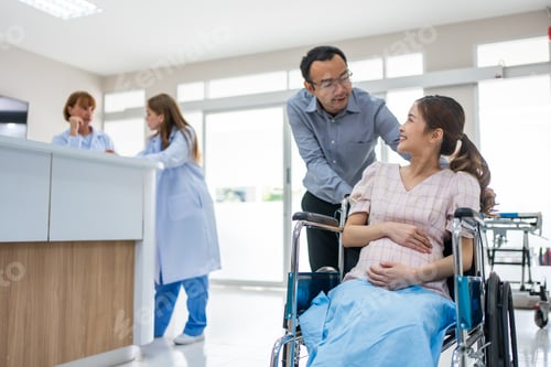Preview: Asian husband taking care of pregnant woman sitting on wheelchair.