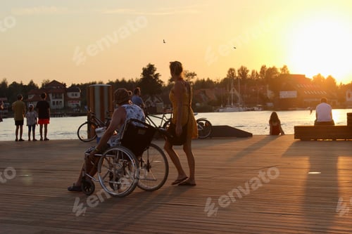 Preview: People using wheelchair.Tourist, wheelchair, sunset, outdoors, summertime.