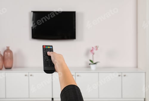 Preview: Woman switching channels on TV set with remote control at home