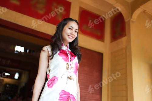 Preview: Happy asian woman in Cheongsam at front of chinese gate in temple during Chinese new year