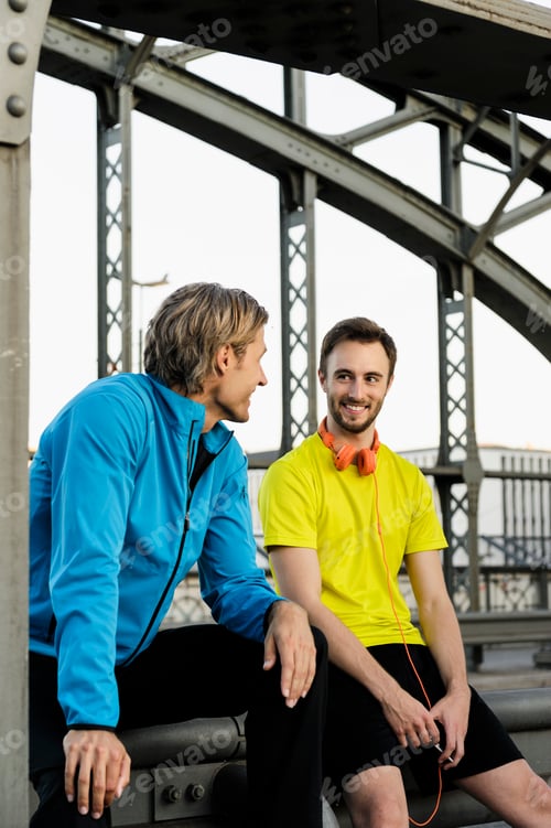 Preview: Two male runners chatting on bridge