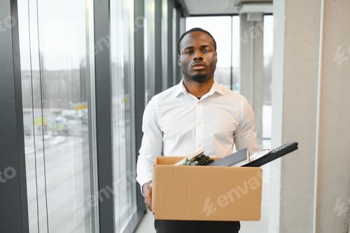 Preview: Young african man fired holding box with personal items at business office