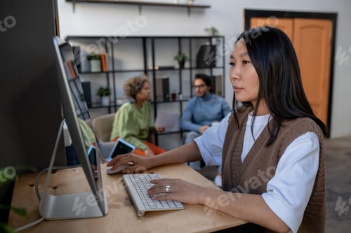 Preview: Young Asian businesswoman in casual clothes working in front of computer monitor