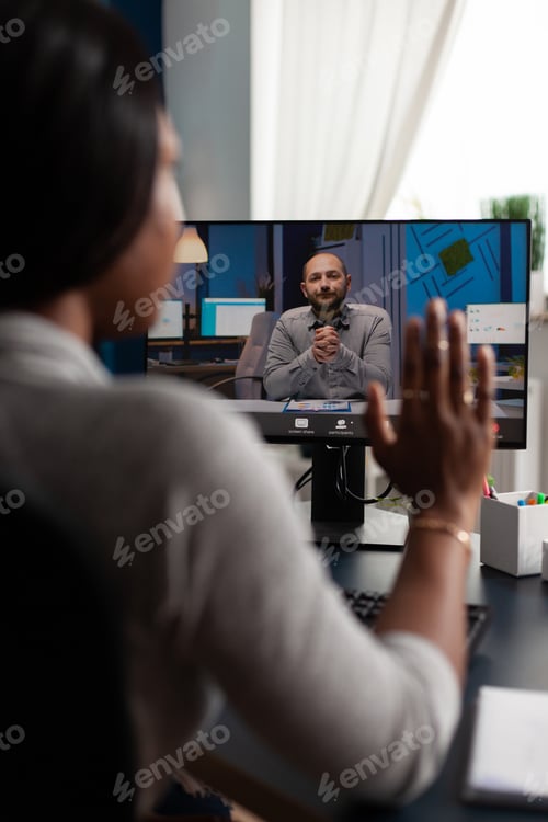 Preview: Woman waving hand at video call webcam with manager