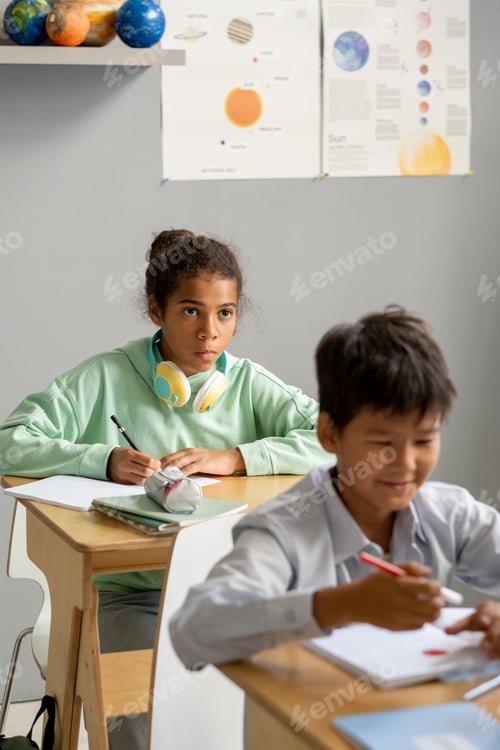 Preview: Cute African-American schoolgirl looking at blackboard or teacher
