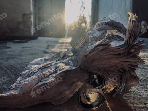 Preview: An old shabby unnecessary spoiled book with torn twisted pages lies on a dirty earthen dark floor