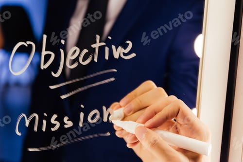 Preview: Smart business man writing the word Objective Mission on the mirror board