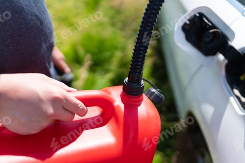 Preview: The driver fills up the empty tank of the car from a red canister on the side of the road.